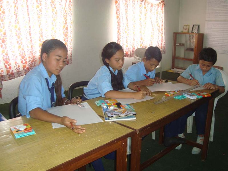 Vier Nepalese kinderen werken gezamenlijk aan een huiswerkopdracht