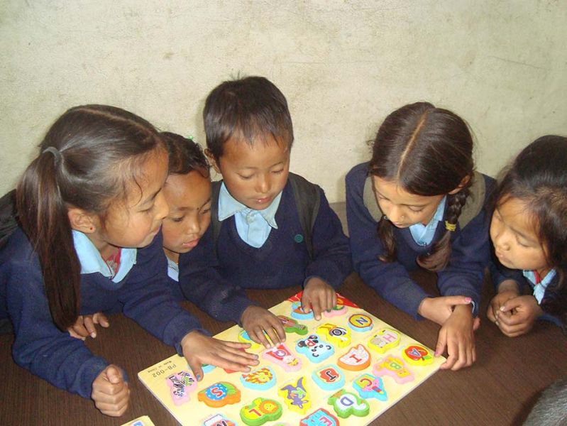 Vijf Nepalese kinderen spelen een spelletje tijdens de lunchpauze.